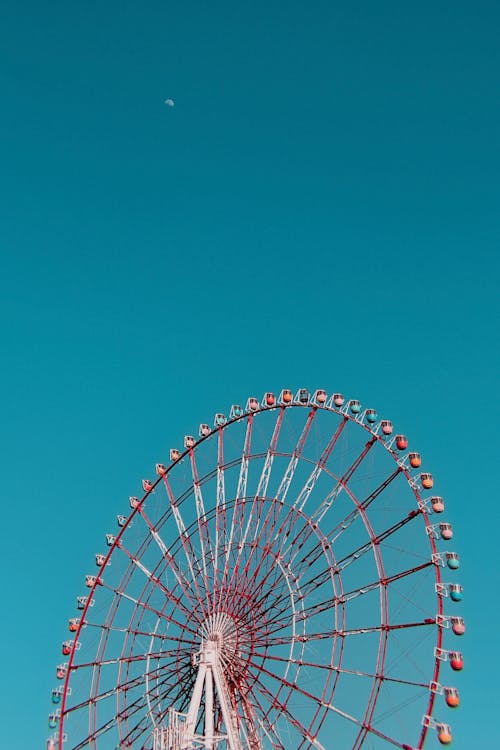 Free A captivating view of a colorful Ferris wheel set against a clear blue sky, evoking a sense of adventure. Stock Photo