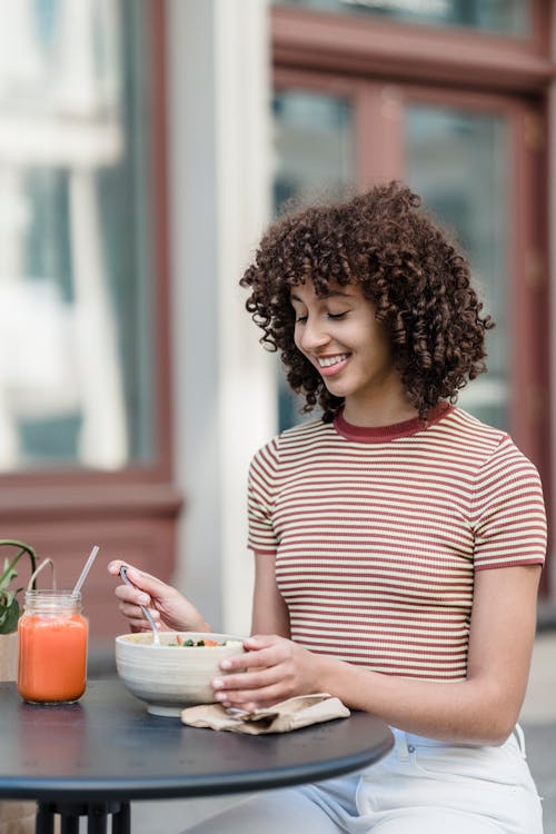 Free Cheerful ethnic woman with delicious lunch and smoothie in cafe Stock Photo
