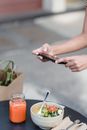 Crop blogger taking photo of vegan salad on smartphone