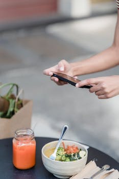 A person takes a photo of a vegan meal and juice, showcasing healthy and organic lifestyle.