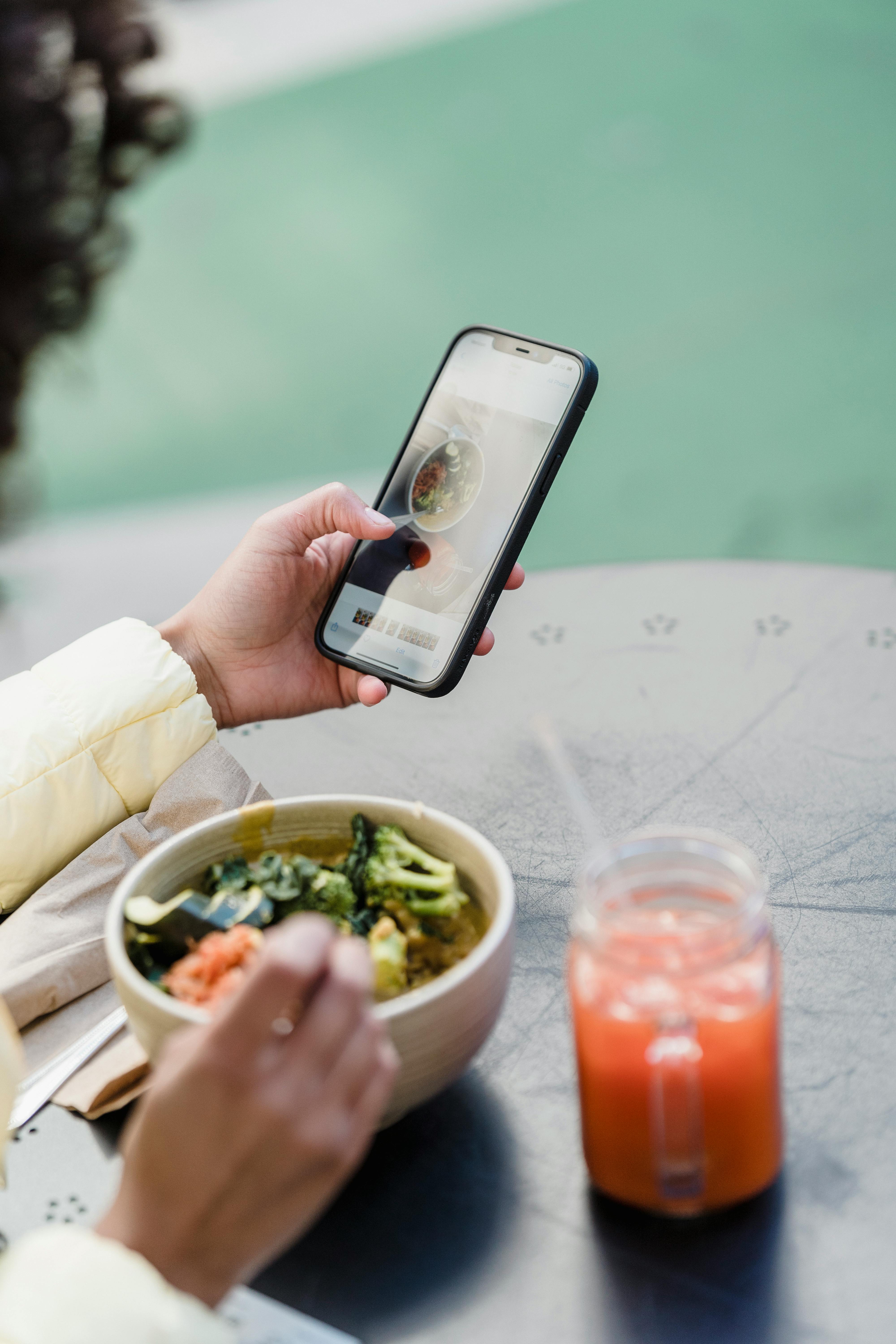 crop blogger with smartphone and tasty vegetarian salad in cafeteria