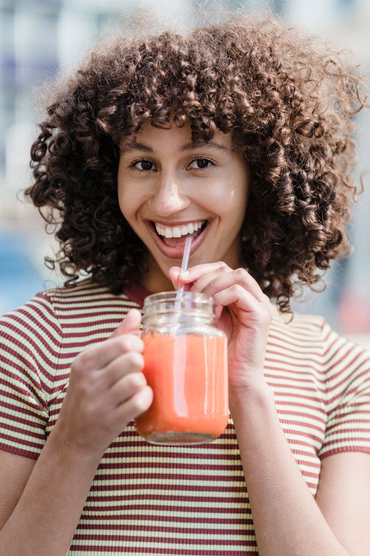 Happy Ethnic Woman Drinking Delicious Smoothie In Urban Cafe