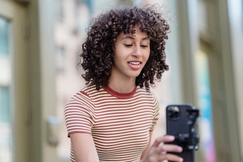 Confident young ethnic woman taking selfie on smartphone on street
