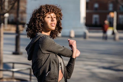 Ethnic woman stretching arms on street