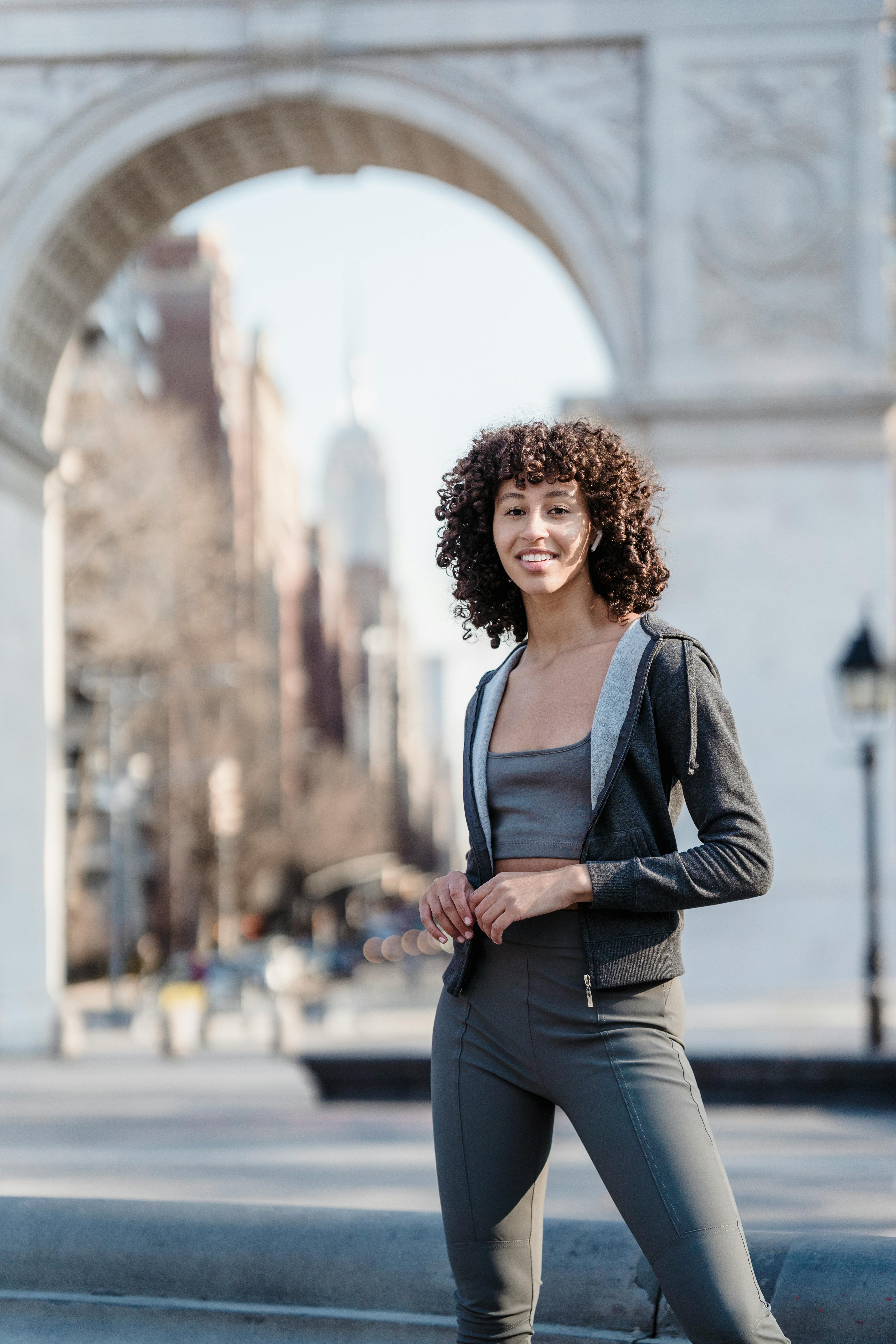 pleasant ethnic woman in activewear near arch