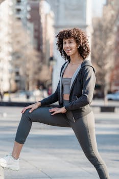 Young woman in activewear stretching in an urban environment, embodying healthy lifestyle and wellness.