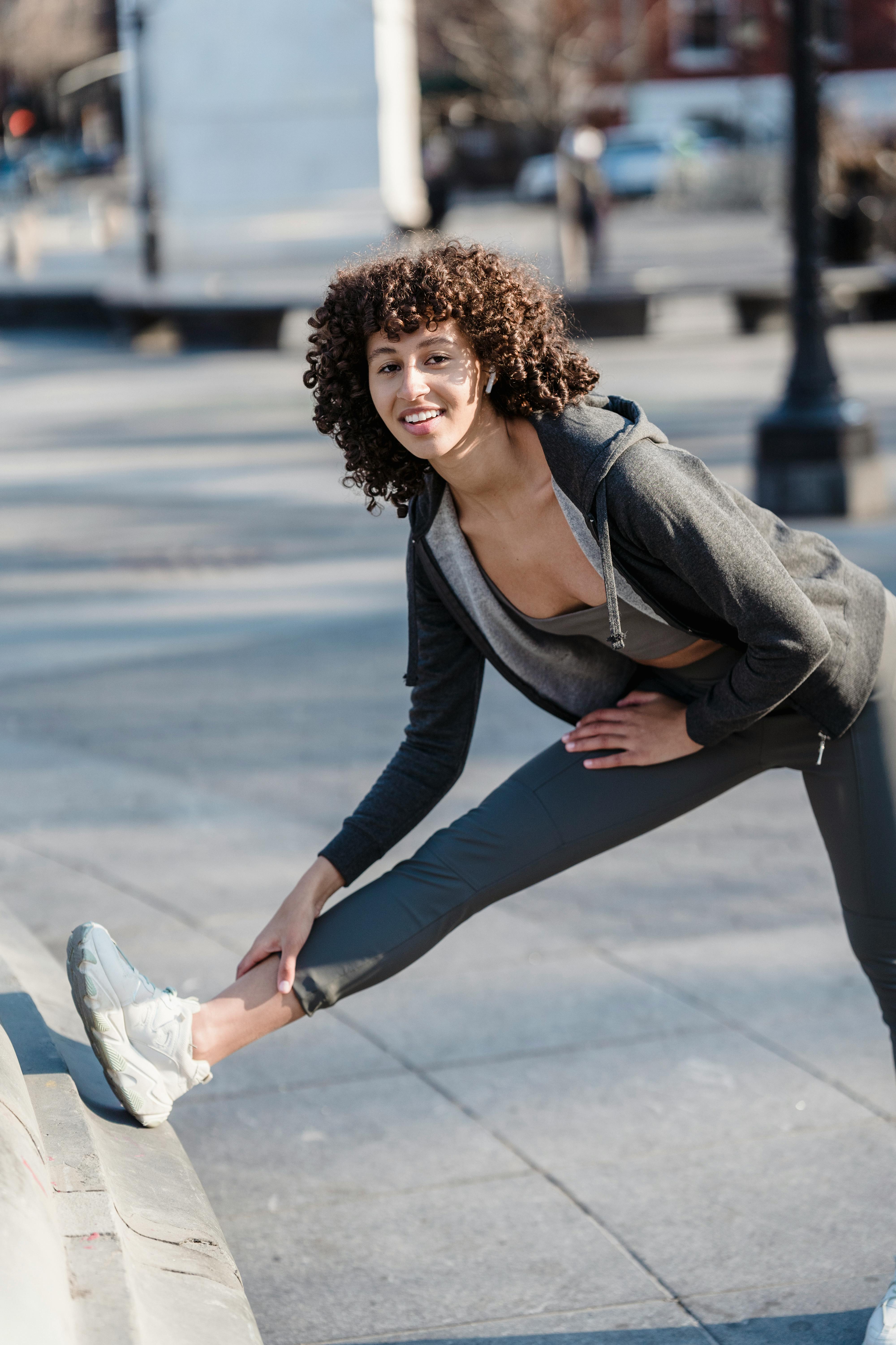 happy ethnic woman in activewear exercising on street