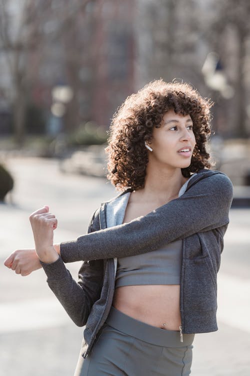 Ethnic woman stretching arms during outdoor workout
