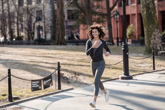 Full body of African American female jogger in sportswear smiling and running in park