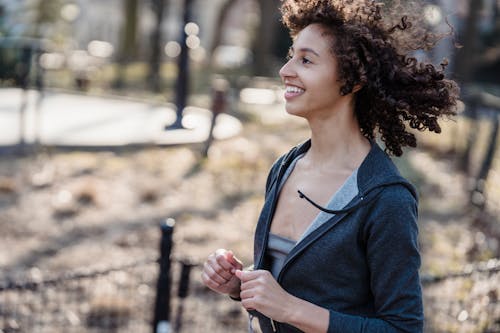Positive black female jogging in park