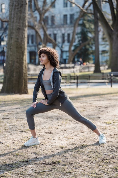 Fit black woman stretching legs in park in daylight · Free Stock Photo