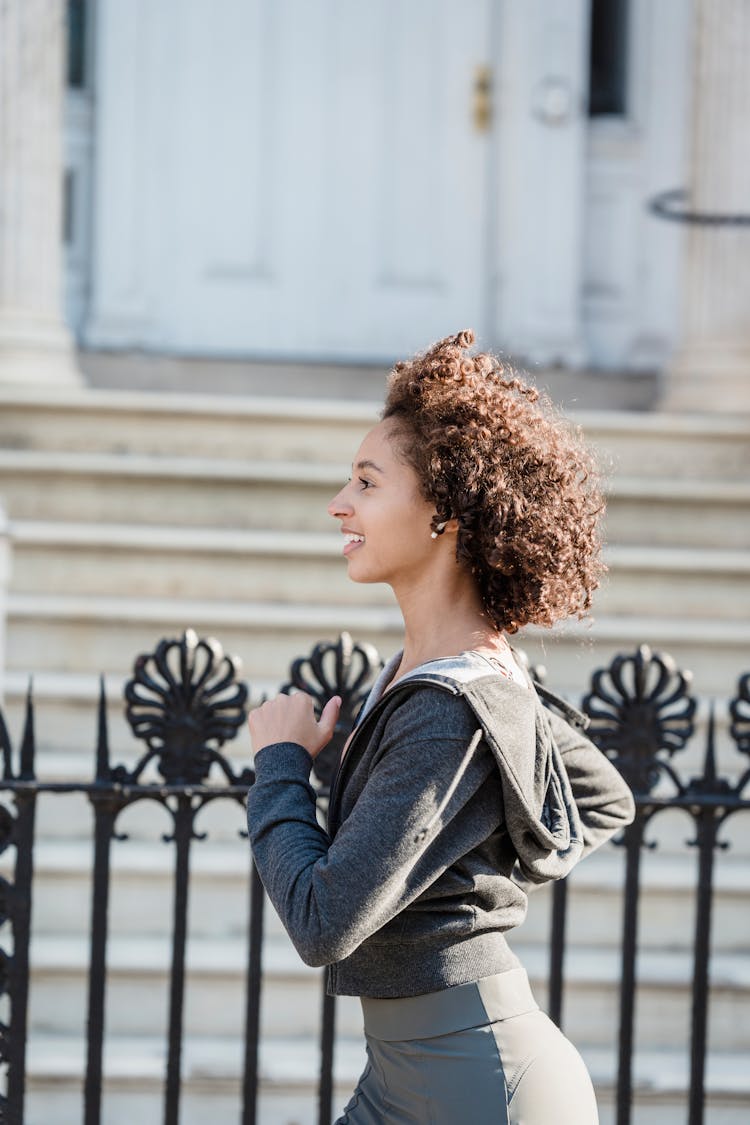 African American Woman Jogging Along Iron Fence