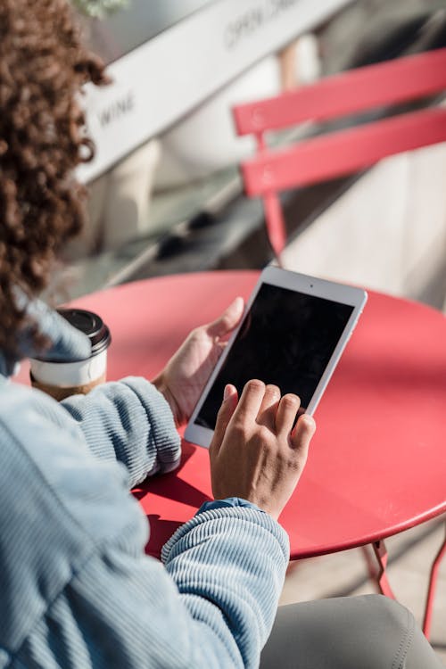 Crop woman touching screen on smartphone at street cafe table