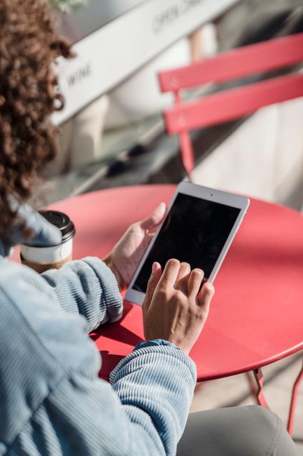 person using tablet outdoors at cafe