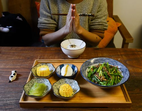 Free A person prays before enjoying a homemade Asian meal featuring vegetables and rice. Stock Photo