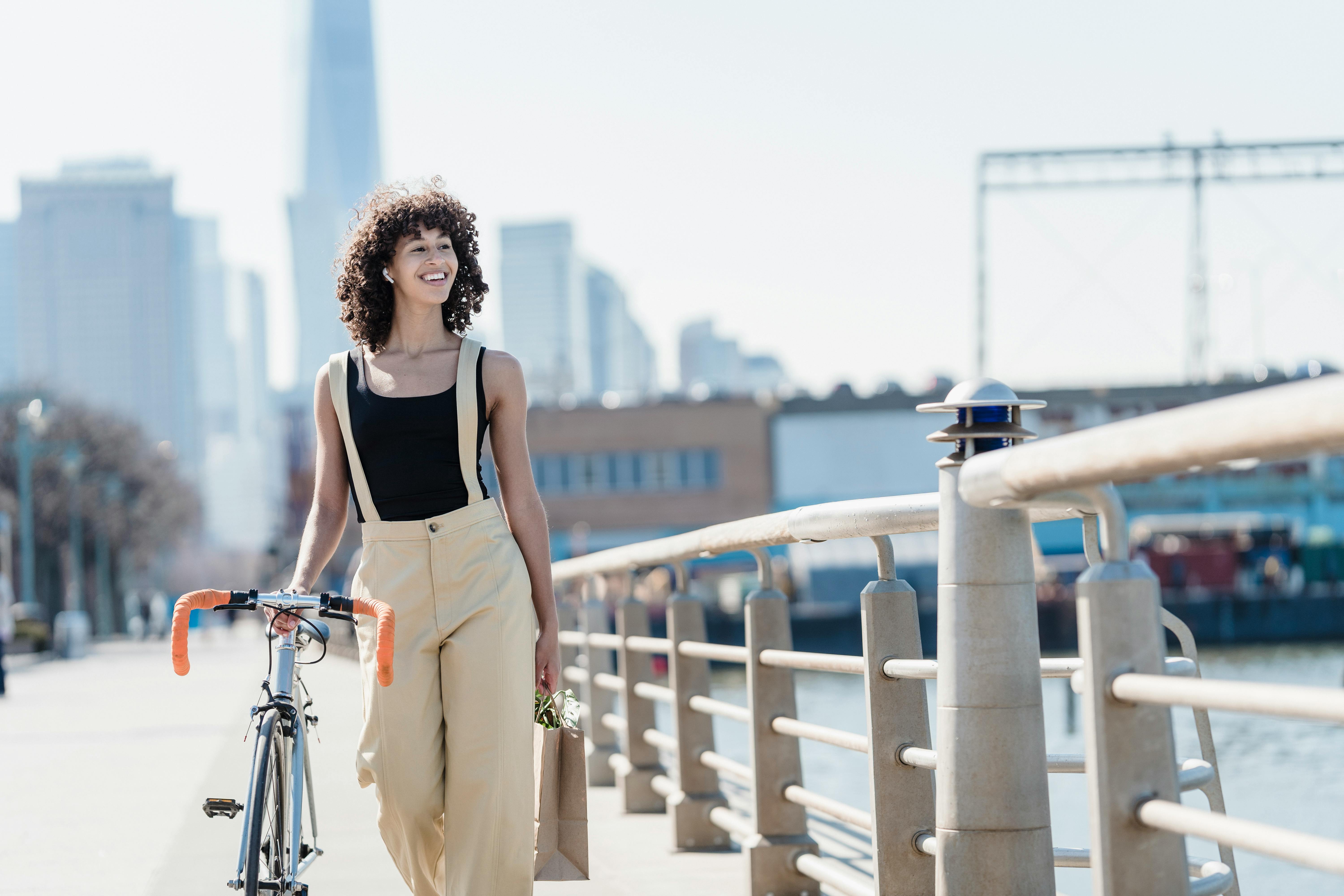 happy ethnic woman with bicycle on embankment