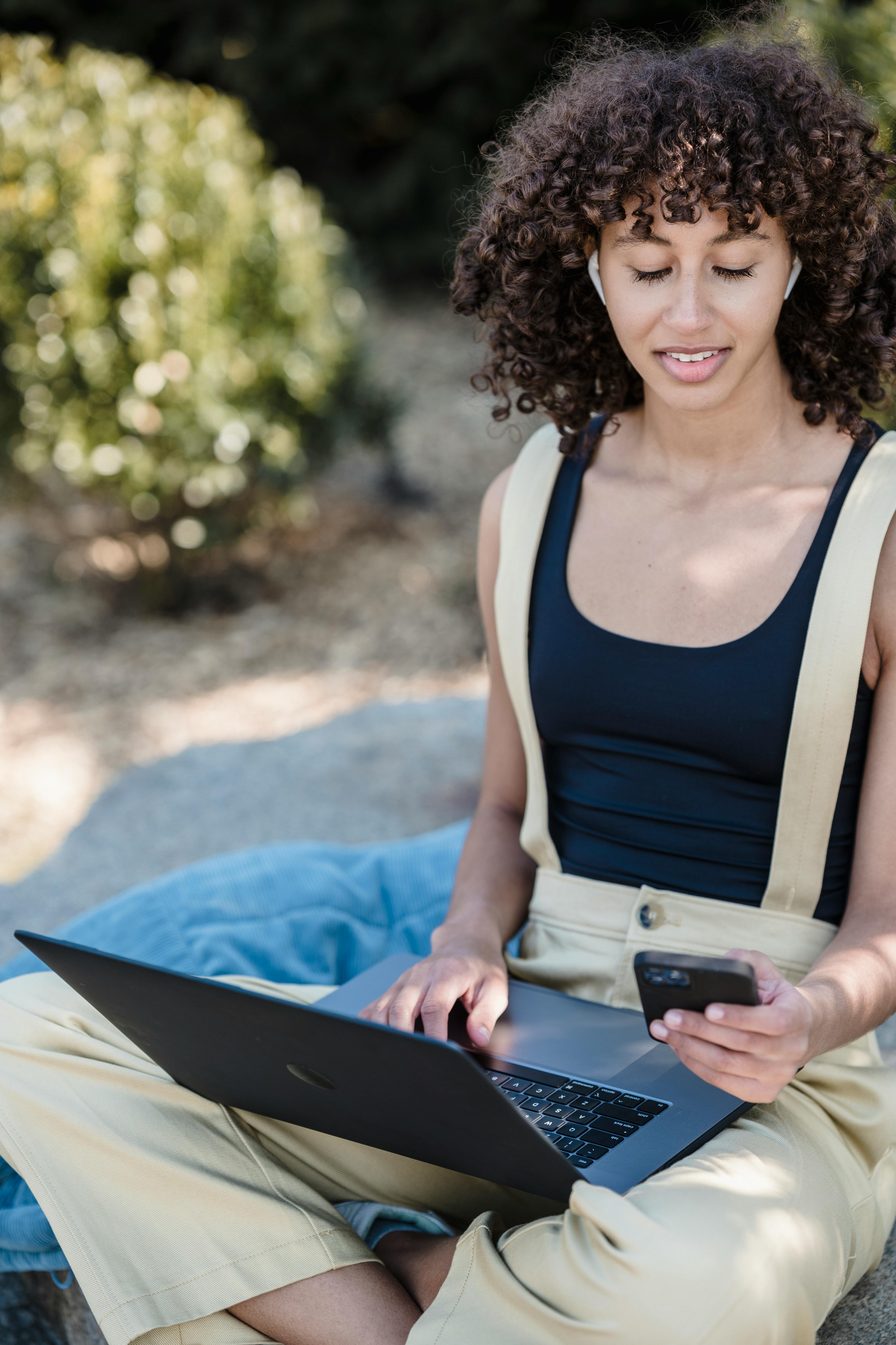 ethnic woman using modern gadgets in park