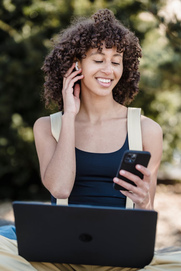 Satisfied Black Woman With Smartphone And Laptop In Park