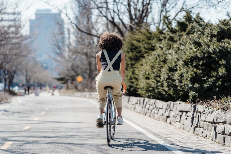 Female Cyclist Riding Bicycle On City Street