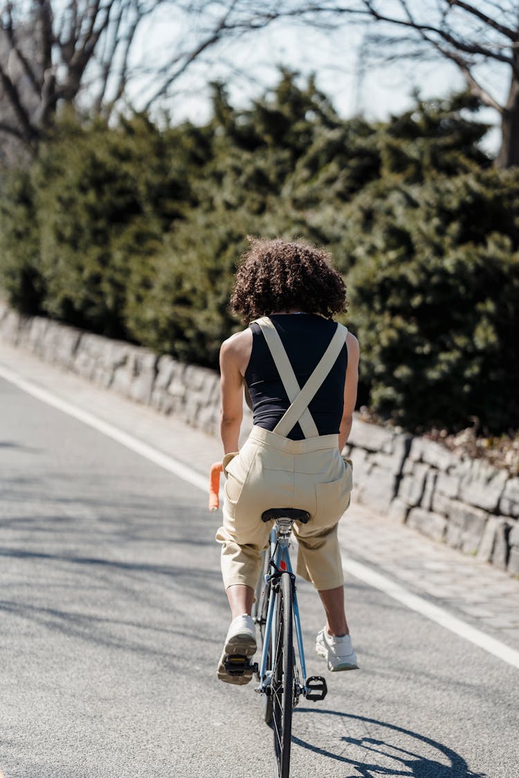 Black Woman Riding Bicycle On Asphalt Road