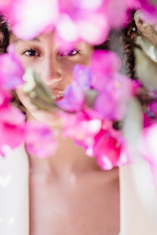 Happy ethnic woman among blooming bright pink flowers