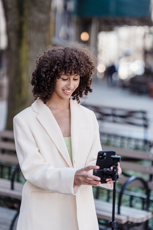 Smiling ethnic blogger with smartphone in city