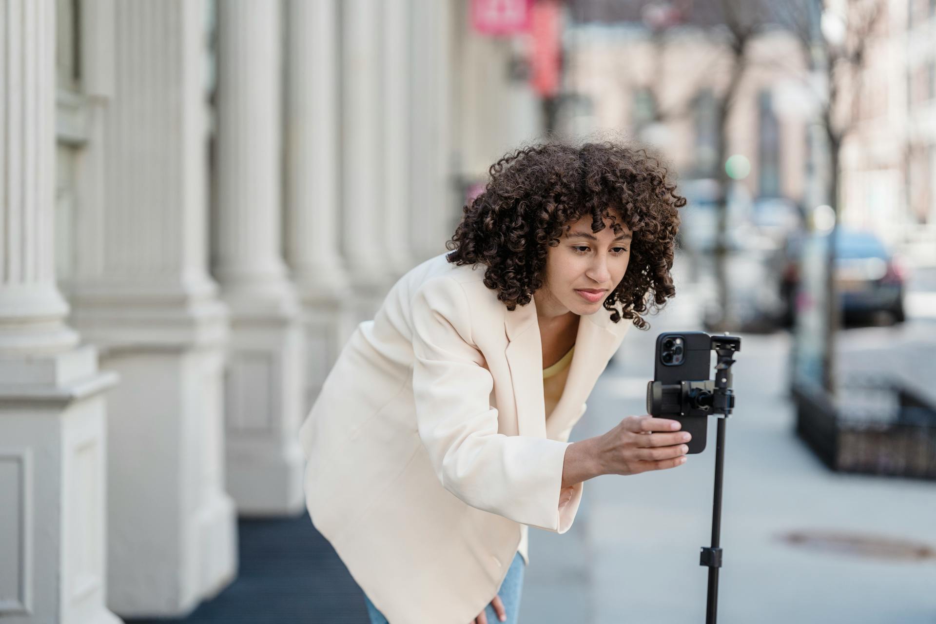 Focused ethnic blogger with smartphone in town