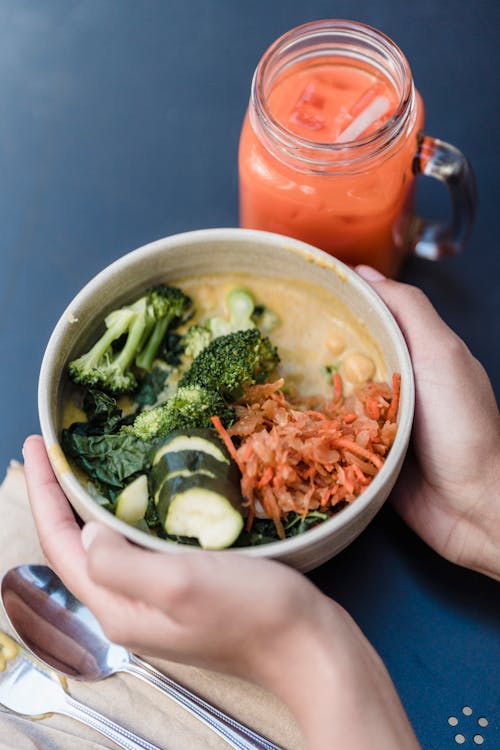 Faceless person with delicious vegetable dish and smoothie in cafe