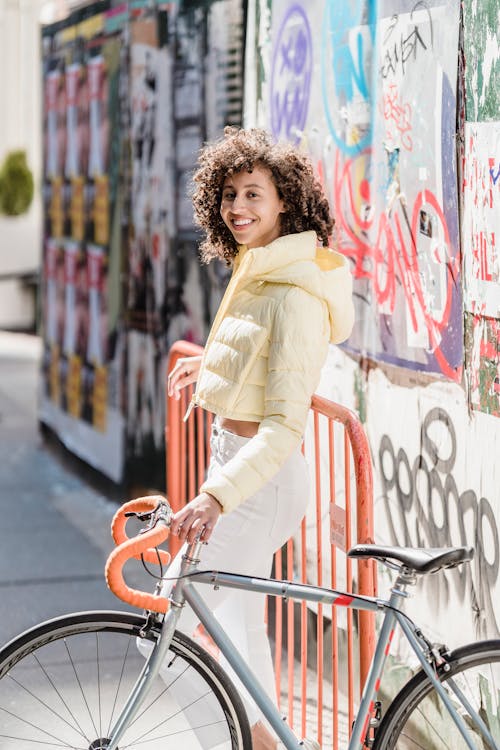 Cheerful ethnic woman with bike on urban pavement