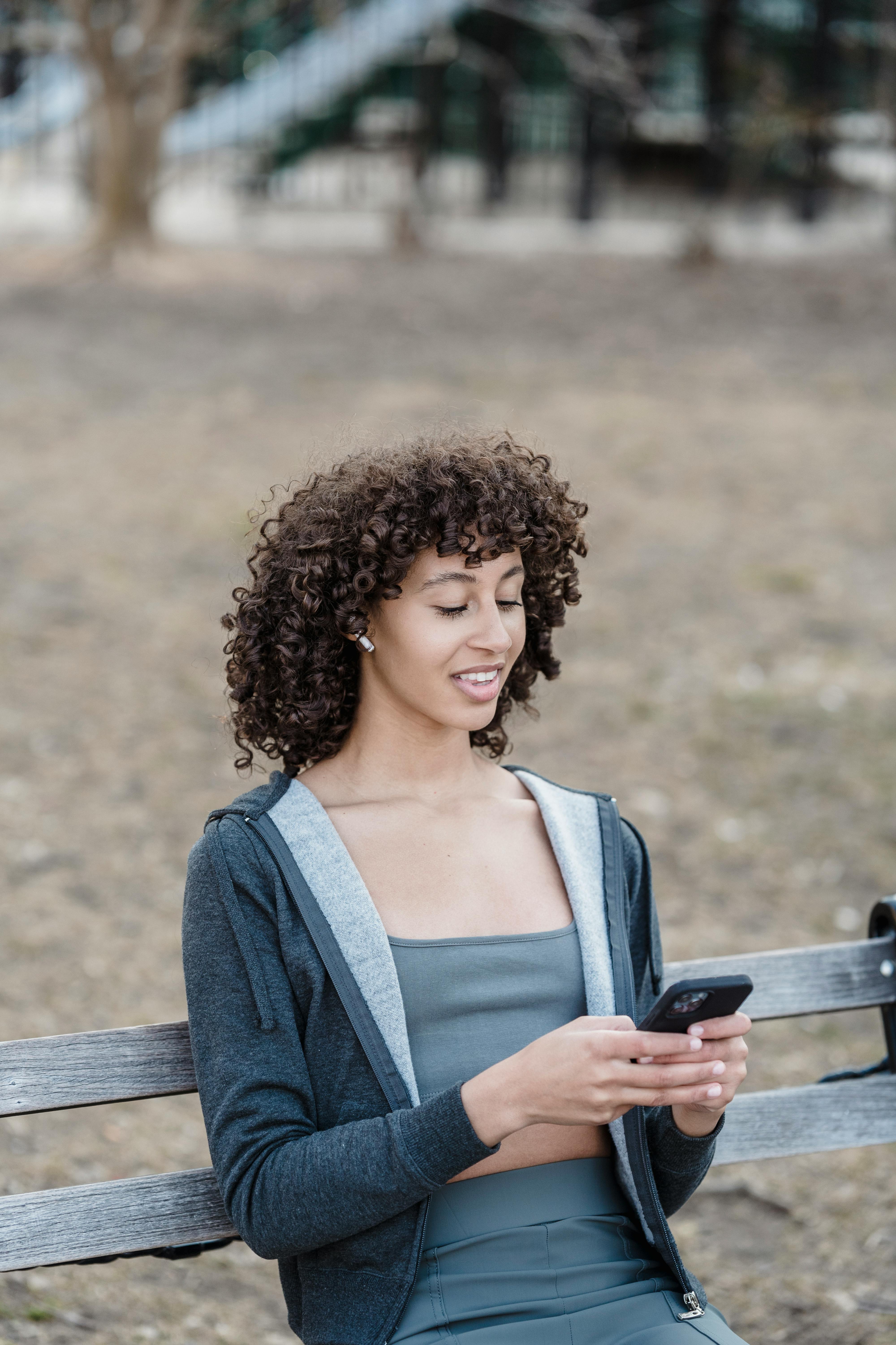 a woman using her smartphone while sitting on a bench