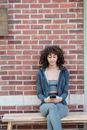 Ethnic curly haired sportswoman browsing smartphone on bench