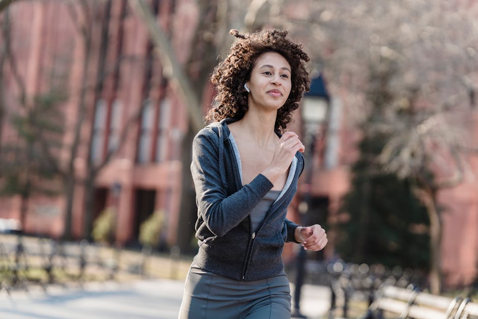 Active young woman jogging outdoors in a park while listening to music, enjoying a healthy lifestyle.