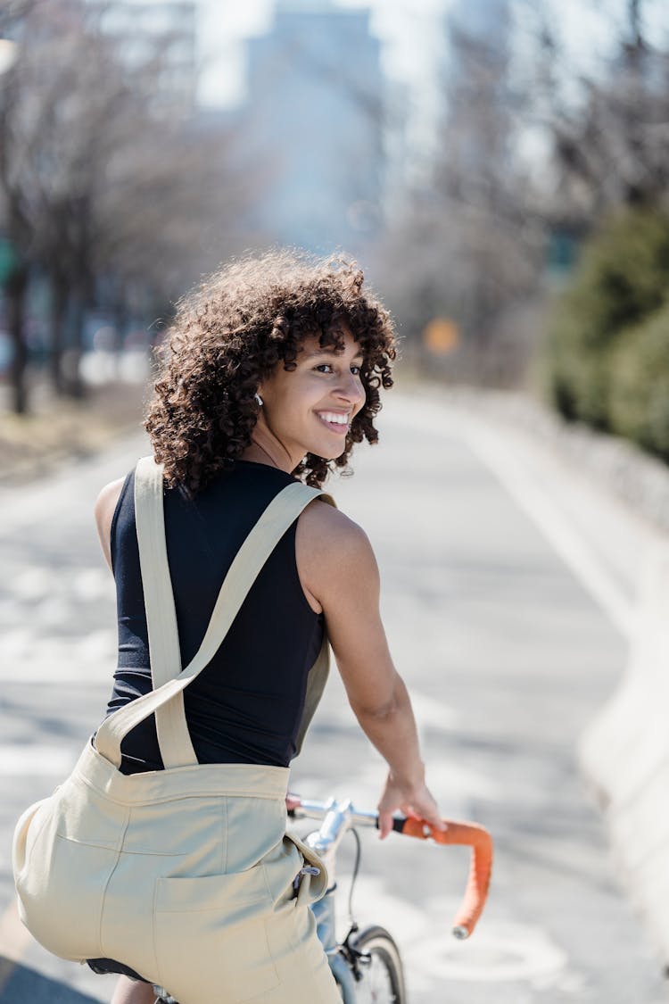 Cheerful Ethnic Woman Riding Bicycle In Park