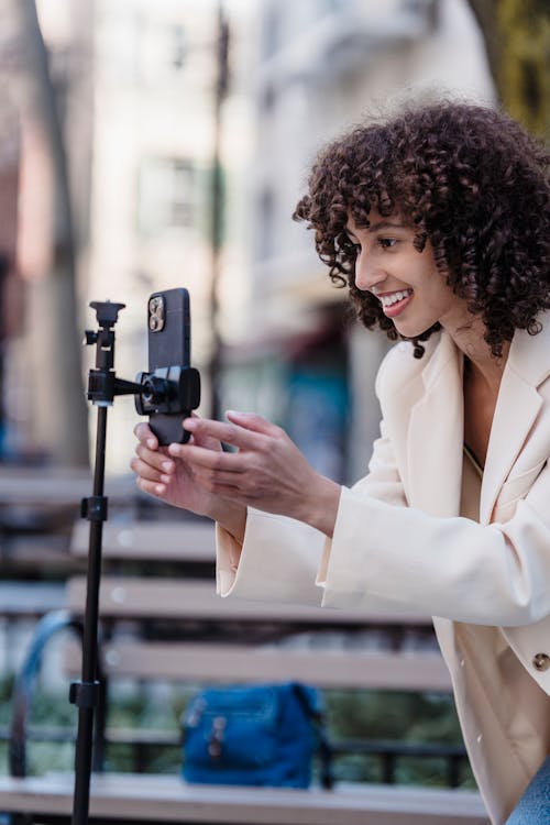 Smiling ethnic woman recording video on smartphone