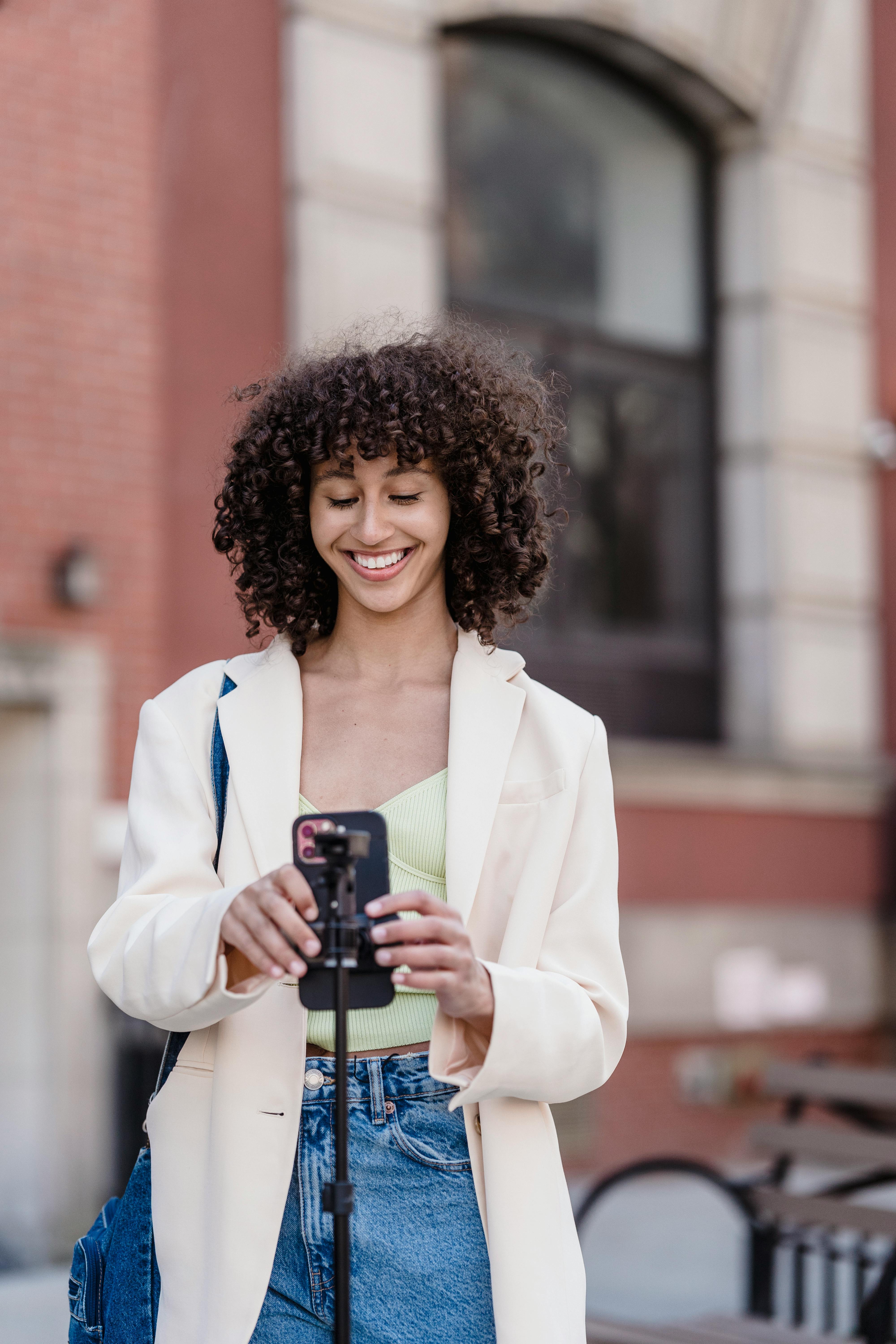 smiling ethnic woman going live on street