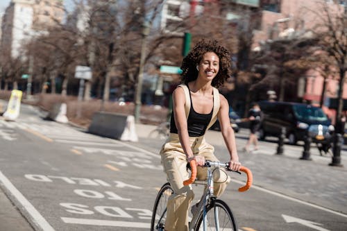 A Smiling Woman Riding a Bicycle in the City