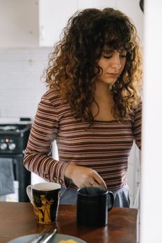 Young woman with curly hair making coffee in an Istanbul kitchen.