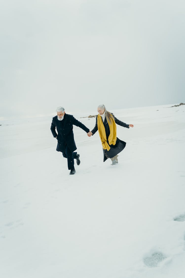 Elderly Couple Holding Hands On A Snowy Field