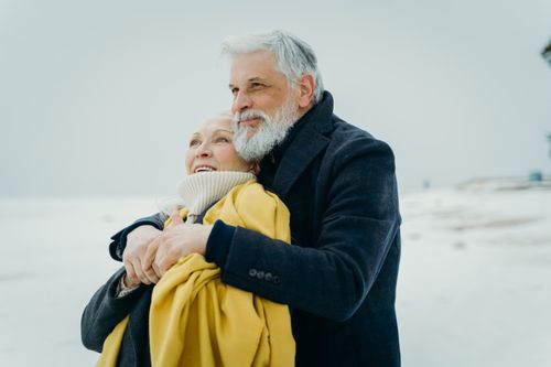 Free Elderly couple embracing warmly on a snowy beach. Love and connection in winter. Stock Photo