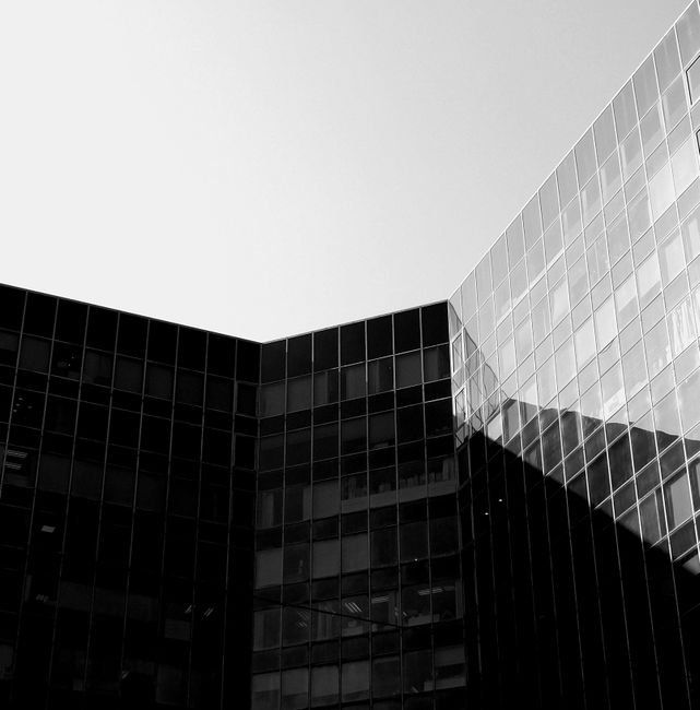 Black and white of contemporary building with glass walls under cloudless sky in sunny day
