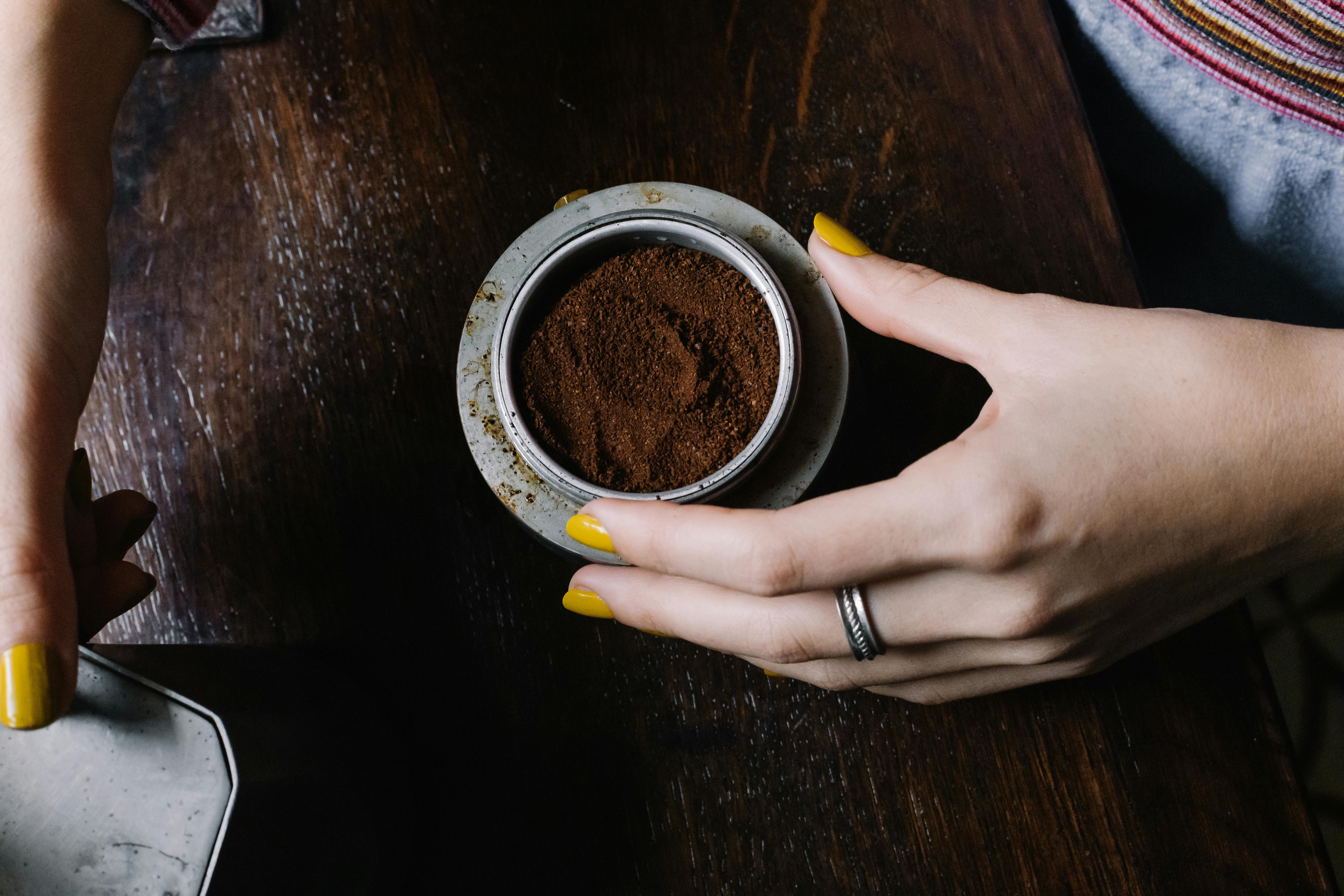 woman holding a bowl of ground coffee powder