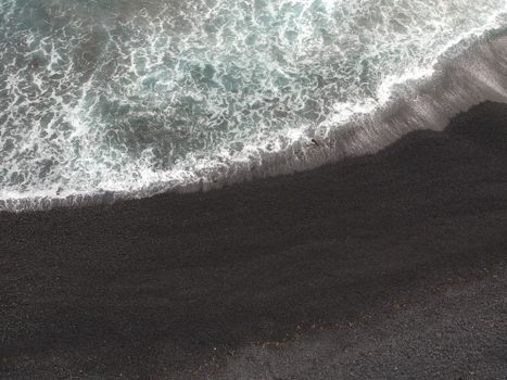 Aerial view of waves crashing on a black sand beach in Iceland, showcasing the natural beauty of the seashore.. pexels, aeria