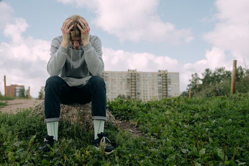 Free A man sitting with head in hands outdoors, showing stress and contemplation. Stock Photo