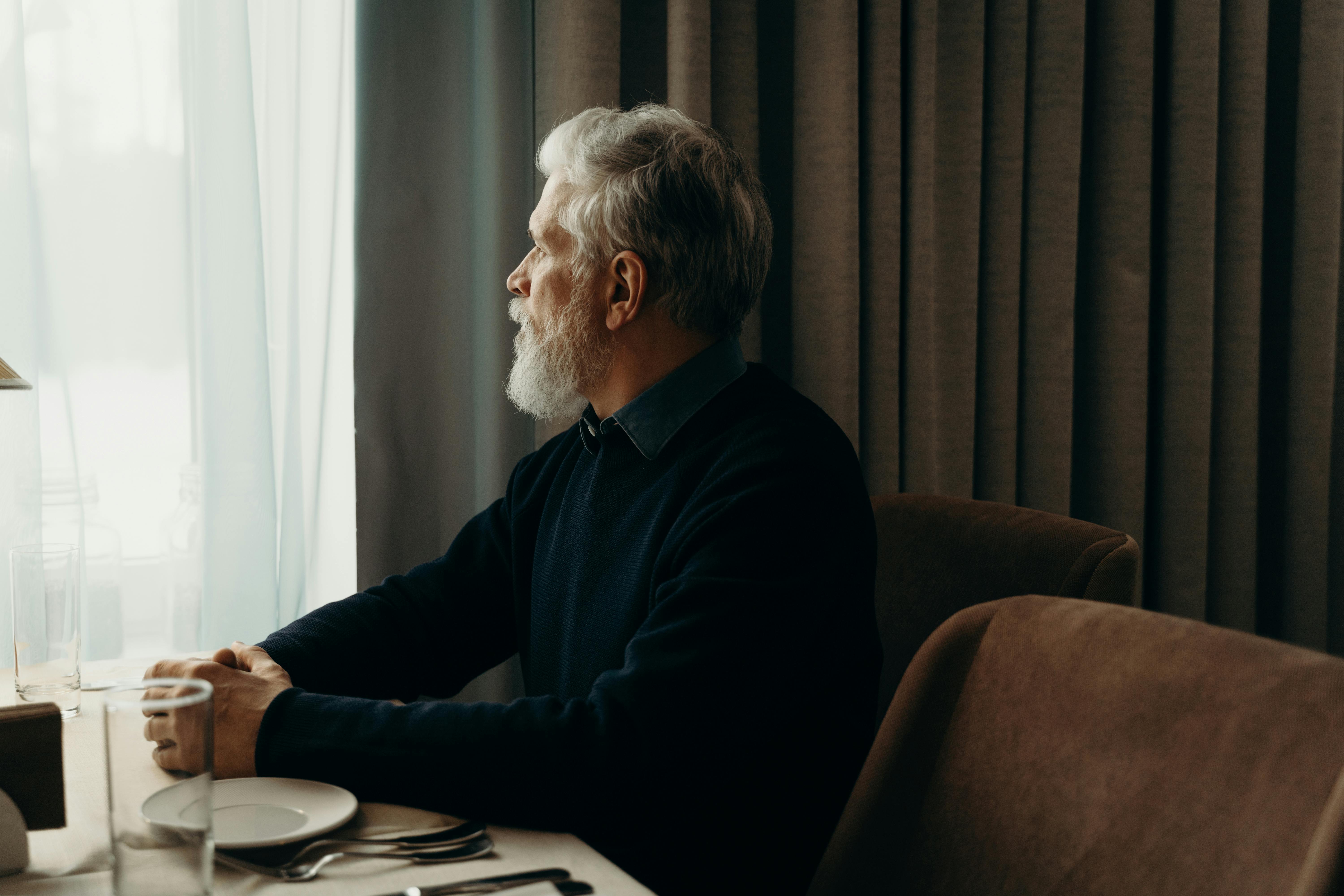 An Eldery Man Sitting at a Laid Table and Looking Through the Window · Free  Stock Photo