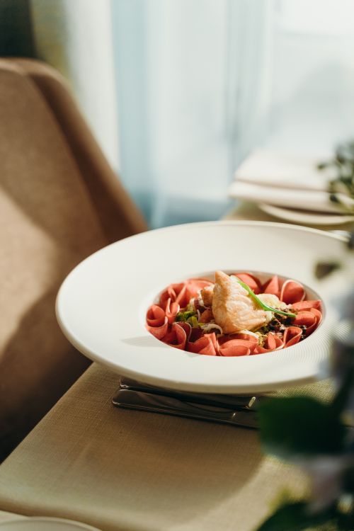 Free A beautifully plated gourmet dish on a sunlit dining table, showcasing an exquisite culinary presentation. Stock Photo
