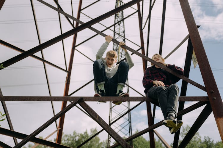 2 Boys Climbing On Brown Metal Ladder