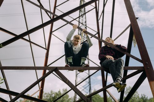 Free Two teenagers sitting and climbing on an electricity pylon with a carefree attitude. Stock Photo