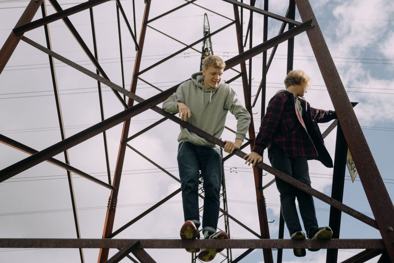 two teenagers climb a power line tower enjoying a daring outdoor adven