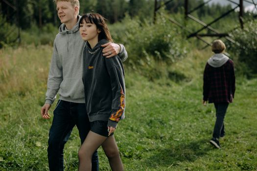 Young Man Walking with Arm around Girlfriend and Brother Walking Away 