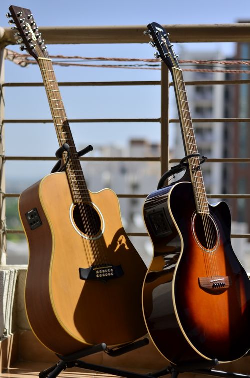 Free Two acoustic guitars resting on a balcony, capturing a musical moment in the sunlight. Stock Photo